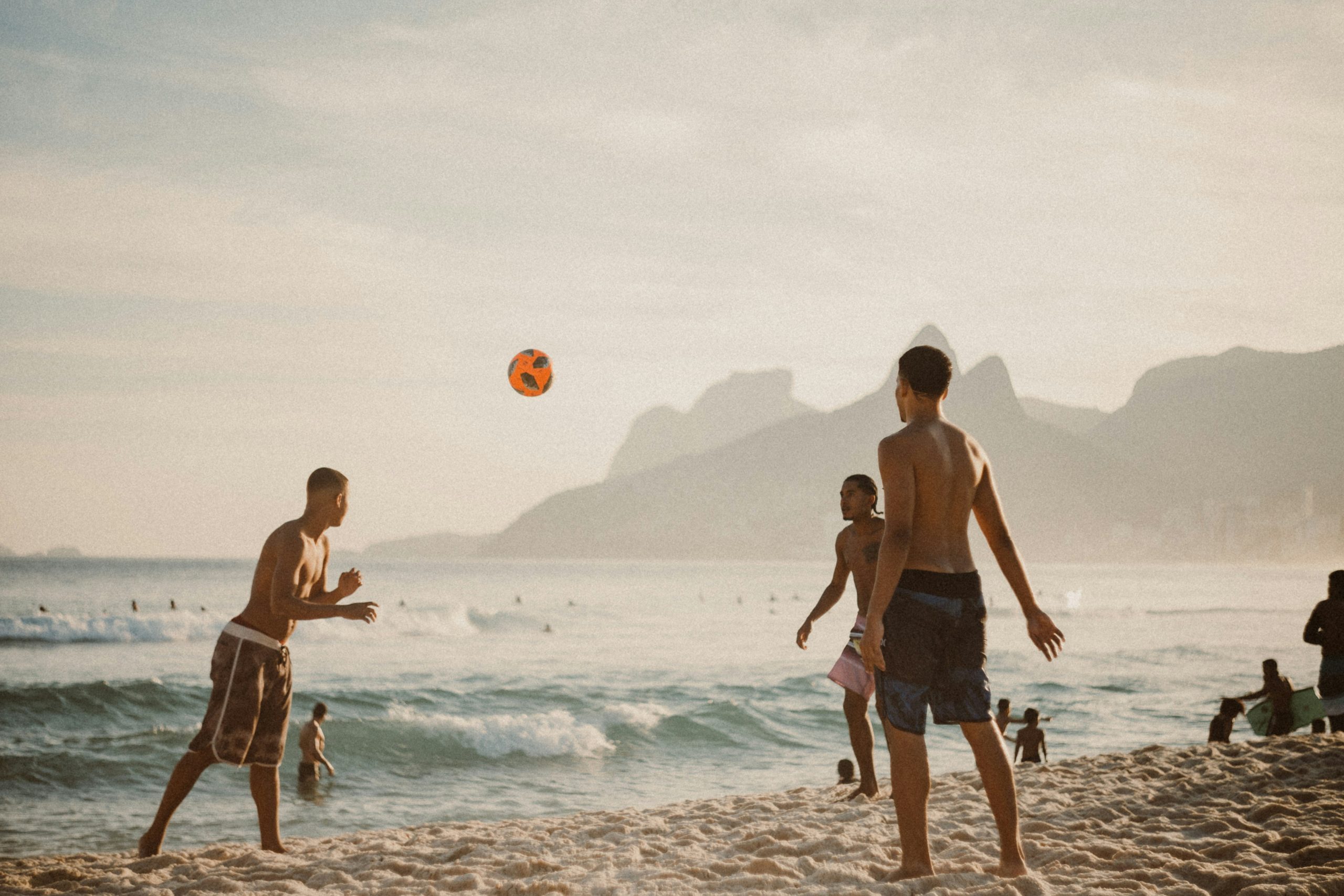 Students on beach playing football.